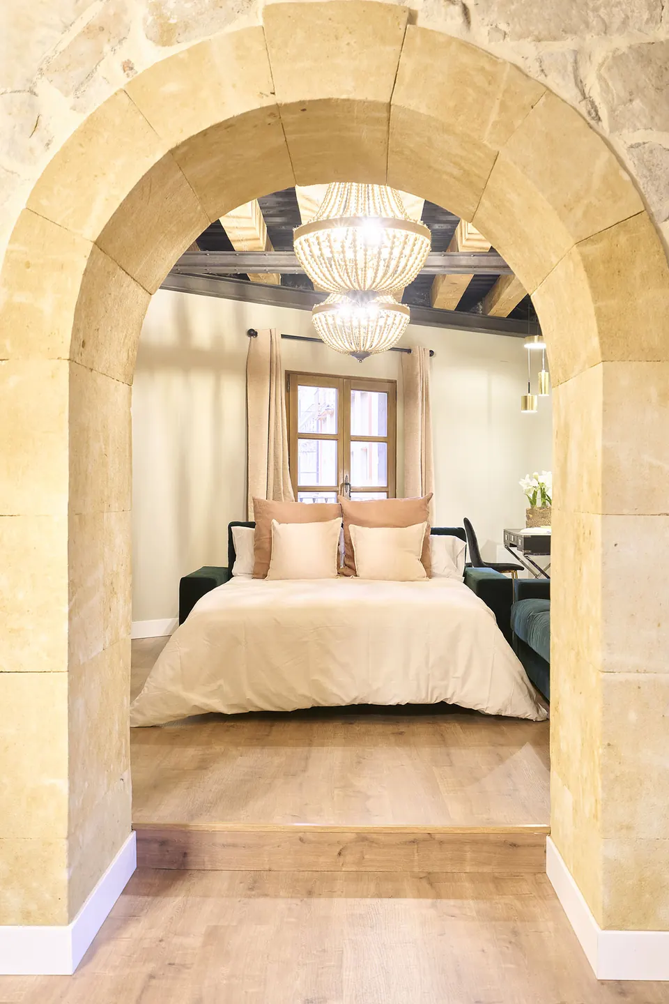 Arco de piedra que da paso a una cama de matrimonio bajo lámparas de cuentas