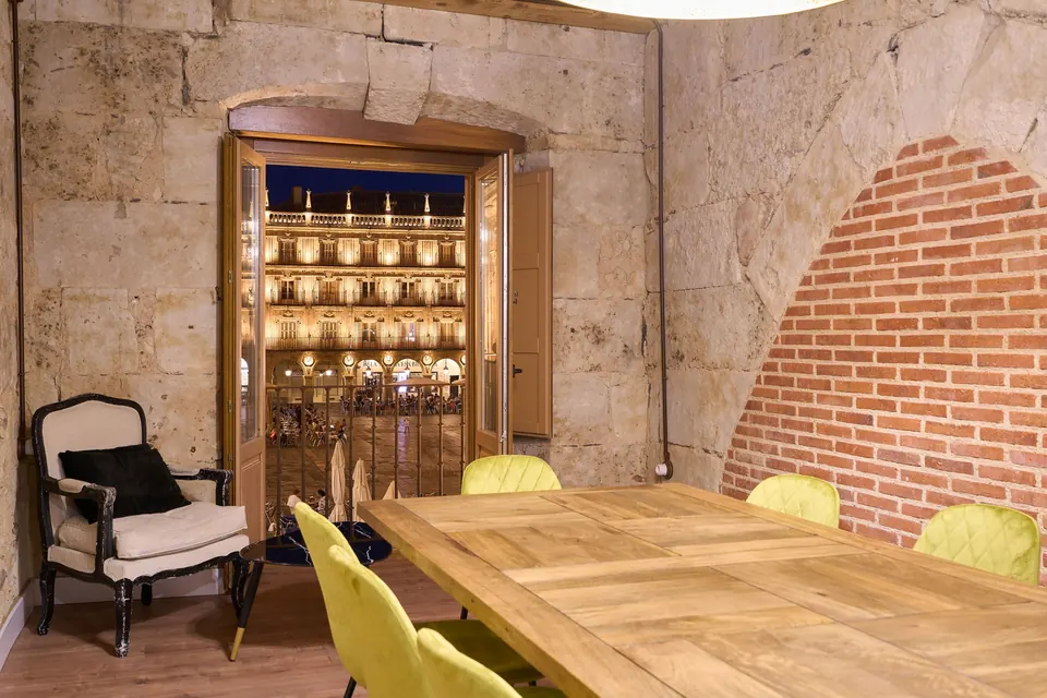 Comedor con mesa de madera, sillas de terciopelo y balcón a la Plaza Mayor