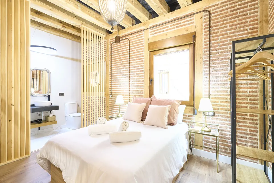 Dormitorio de ladrillo visto con vigas de madera y baño integrado