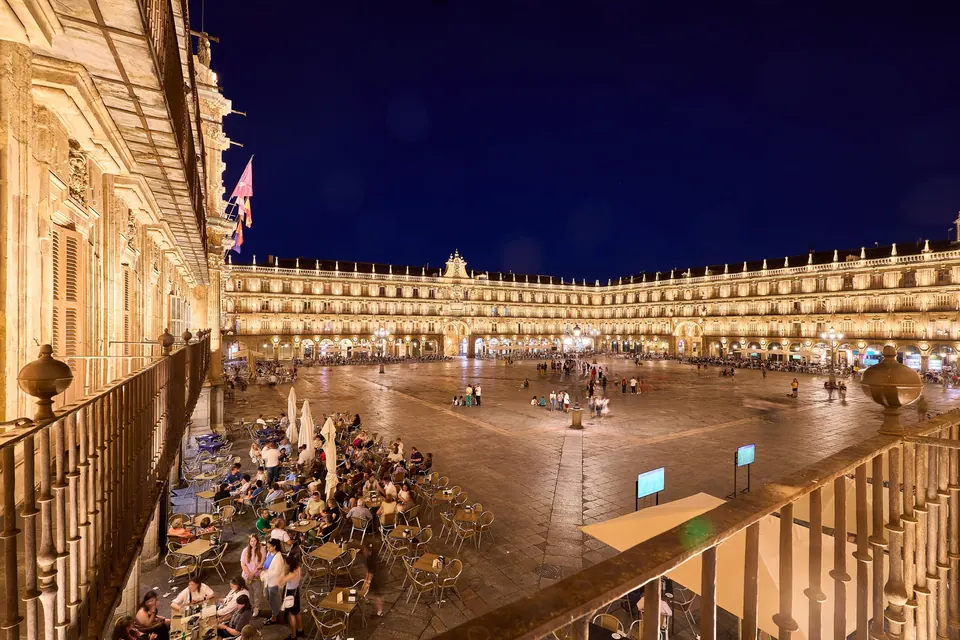 Vista nocturna de la Plaza Mayor de Salamanca desde el balcón, con terrazas llenas